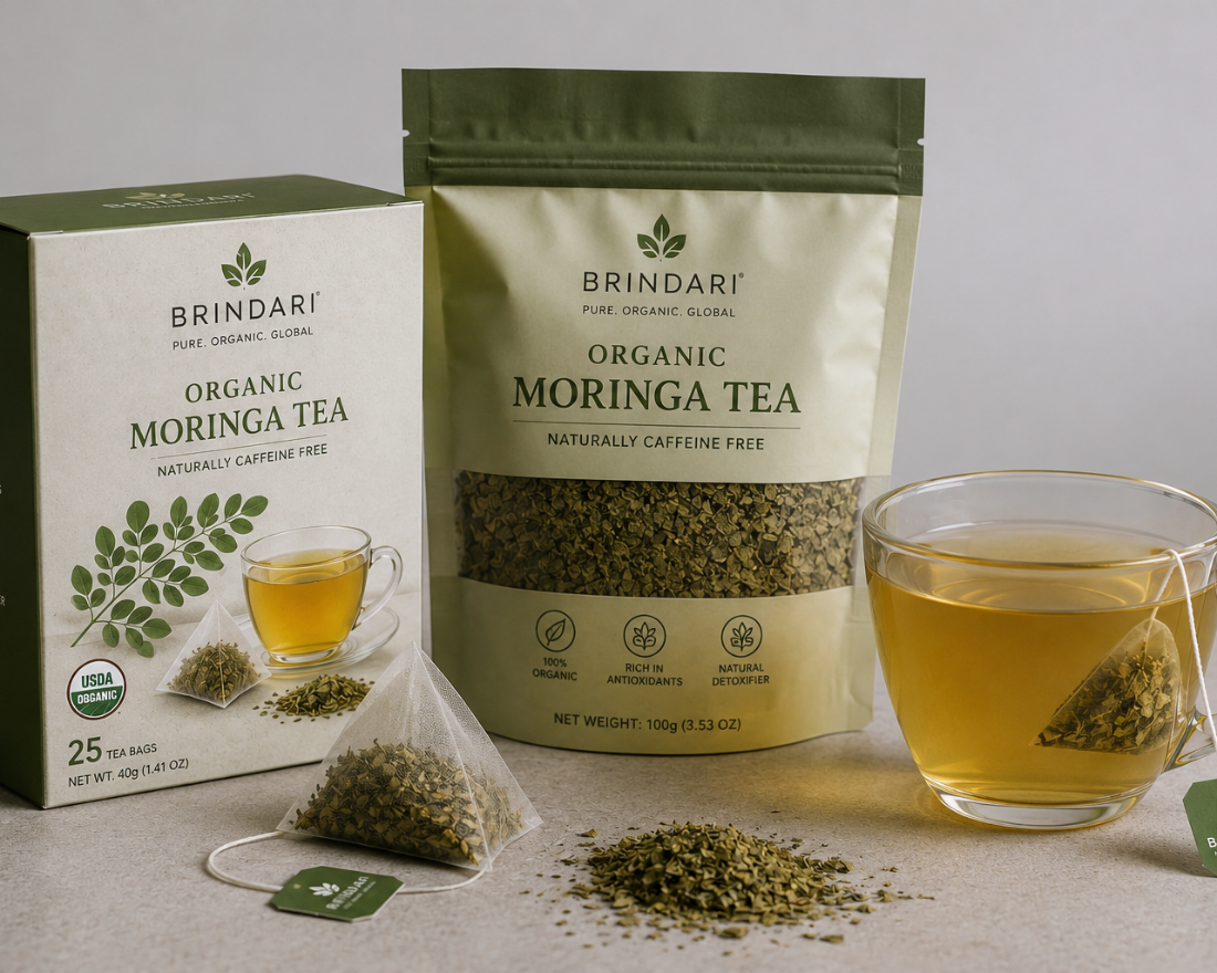 Brindari Organic Moringa Tea box and stand-up pouch beside a glass cup of brewed tea and a pyramid sachet